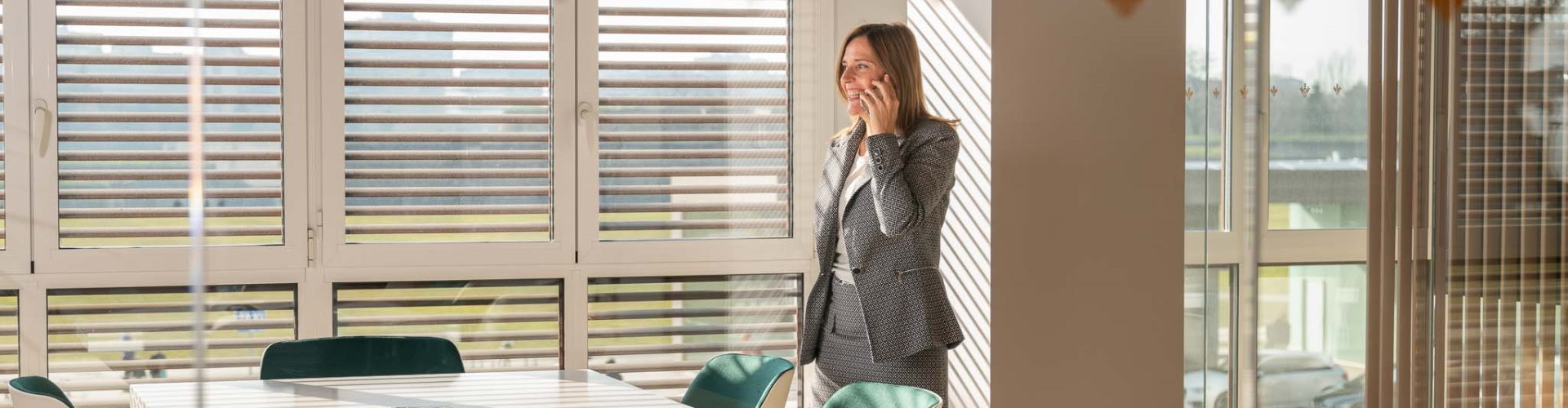 Pagos Empresas - Mujer con traje hablando por el móvil en una oficina - Caja Rural de Navarra Pagos Empresas - Mujer con traje hablando por el móvil en una oficina - Caja Rural de Navarra
